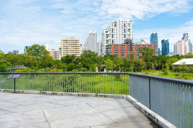 Yeşil ağaç ormanları ve ofis inşaatı ile şehir parkında yürümek doğanın geçmişini gölgeliyor.