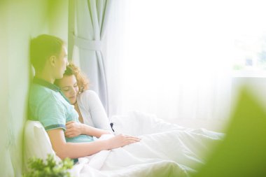 Aşk çifti sabah beyaz yatakta uzanıyor. Mutlular ve birbirlerine sarılıyorlar. Sevginin rahatlığı.