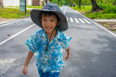 Küçük çocuk şehir parkının patikasında yürüyor. Yeşil orman, açık hava eğlencesi.