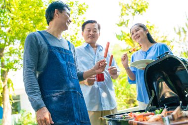 Bir grup kıdemli erkek arkadaş BBQ barbekü partisi ev bahçesinde mutlu emeklilik