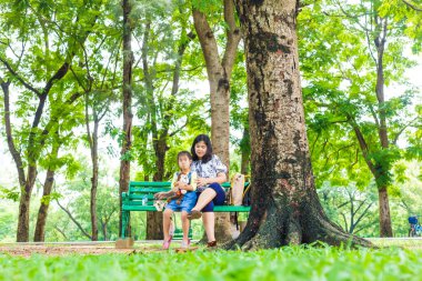 Küçük sevimli Asyalı kız şehirde rahatla. Yeşil Park 'ta anne ile açık hava aktivitesi yap.