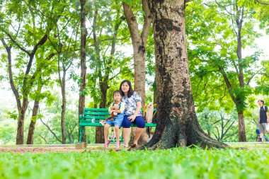 Küçük sevimli Asyalı kız şehirde rahatla. Yeşil Park 'ta anne ile açık hava aktivitesi yap.