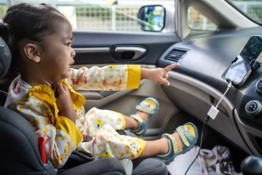 Küçük kız araba koltuğuna oturup eğleniyor kemerini bağla güvenli nakliye yolculuğu