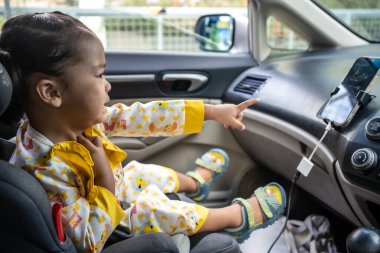 Küçük kız araba koltuğuna oturup eğleniyor kemerini bağla güvenli nakliye yolculuğu