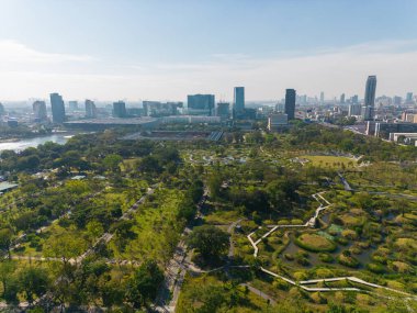 Bangkok Tayland şehir merkezindeki Benchakitti halk parkında tropik yeşil ağaç parkı olan modern ofis binası.