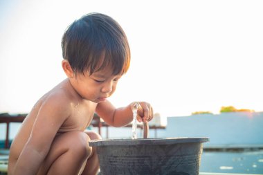 Little preschool happy boy take shower outdoor in basin toddler boy