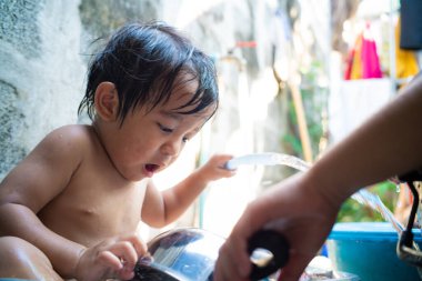 Little preschool happy boy take shower outdoor in basin toddler boy
