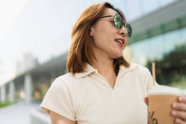 İş dünyasının Asyalı girişimcisi zeki kadın şehirdeki ofis binasında kahve içiyor.