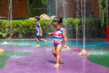 Renkli şehir çocuk parkında yaz tatili konseptiyle eğlenen sevimli küçük kız.