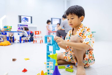 Anaokulundaki çocuk oyuncak bloğu figürleriyle oyuncak inşaat şantiyesini öğreniyor.