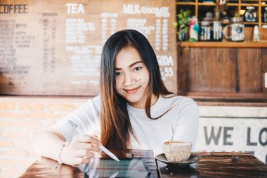 Sanat kafede oturan Asyalı iş kadını iş iletişimi teknolojisi konsepti için tablet kullanıyor