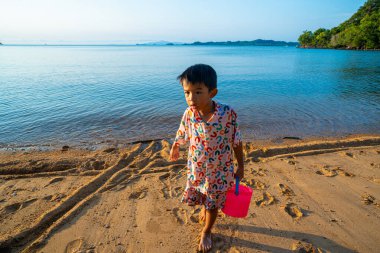 Sahilde deniz suyu oynayan Asyalı çocuk gün batımında hafif doğa tatili konsepti