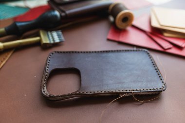 Deri arka plan üzerinde çalışan el yapımı hakiki deri telefon kılıfı ustalığı.