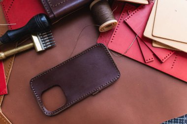 Deri arka plan üzerinde çalışan el yapımı hakiki deri telefon kılıfı ustalığı.