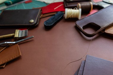 Deri arka plan üzerinde çalışan el yapımı hakiki deri telefon kılıfı ustalığı.
