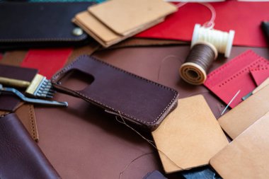 Deri arka plan üzerinde çalışan el yapımı hakiki deri telefon kılıfı ustalığı.