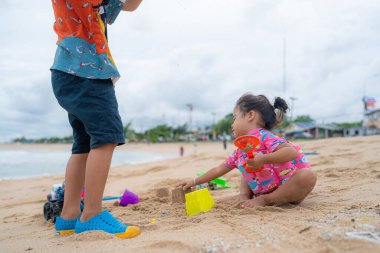 Mutlu Asyalı çocuklar erkek ve kız egzotik deniz plajı yaz tatili konseptinde oyuncak oynuyorlar.