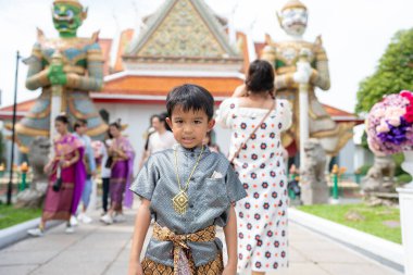 Anaokulu çocuğu geleneksel takım elbise giyer. Şafak vakti Budist tapınağı Wat Arun Bangkok Tayland 'a seyahat eder.