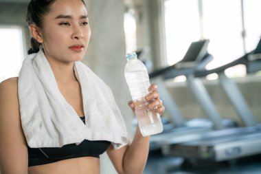 Spor salonundaki kadın sağlıklı yaşam tarzından sonra şişeden su içiyor.