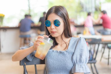 Şehirdeki kafede oturan güzel Asyalı kadın hafta sonu iş kadınını rahatlatıyor.