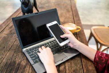 Kadın el ile fincan sütlü kahve boş ekran laptop yazarak