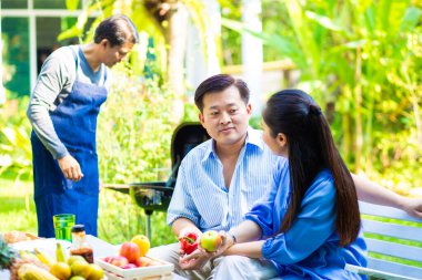 Park 'ta barbekü ızgara yemek partisi veren Asyalı mutlu bir arkadaş.