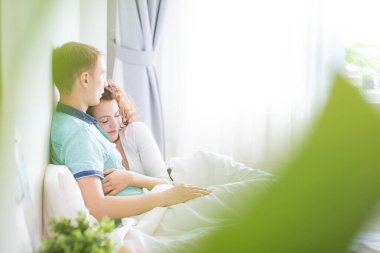 Aşk çifti sabah beyaz yatakta uzanıyor. Mutlular ve birbirlerine sarılıyorlar. Sevginin rahatlığı.