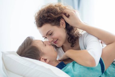 Aşk çifti sabah beyaz yatakta uzanıyor. Mutlular ve birbirlerine sarılıyorlar. Sevginin rahatlığı.