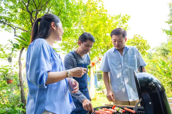 Park 'ta barbekü ızgara yemek partisi veren Asyalı mutlu bir arkadaş.