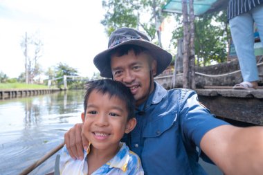 Küçük çocuk nehir boyunca seyahat eder. Tropikal yağmur ormanı ağacı, tahta tekne macerası, mutlu çocuk.