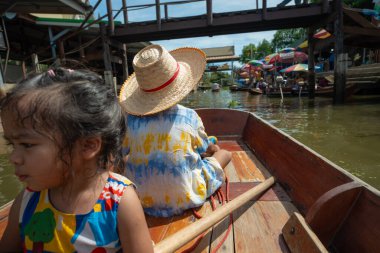 Mutlu çocuk ve kız Damnoen Saduak yüzen Tayland 'da seyahat nehri ahşap teknesinin keyfini çıkarıyorlar.