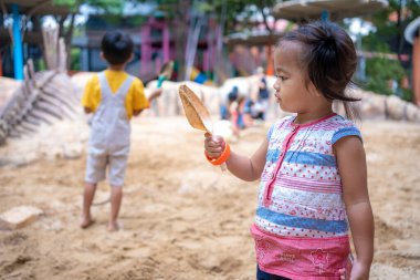Asyalı anaokulu çocuğu ve kızı kum havuzunda oynayıp oyun alanında eğleniyorlar. Açık havada yaratıcı faaliyetler