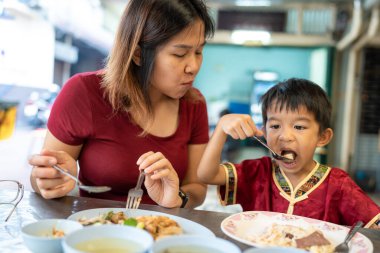 Annesiyle birlikte küçük Asyalı çocuk Yaowarat Bangkok Tayland 'da sokak yemeklerinde pilav yiyor.