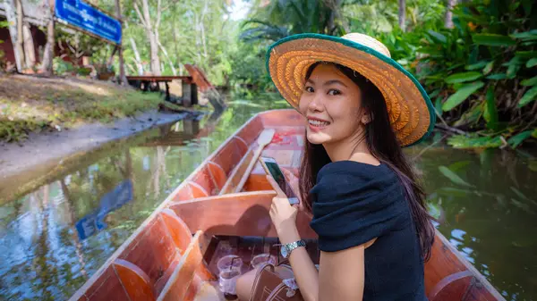 Güzel Asyalı bir kadın batan pazarda tahta bir tekneyle seyahat ediyor tropikal orman nehri gezisi Bangkok Tayland