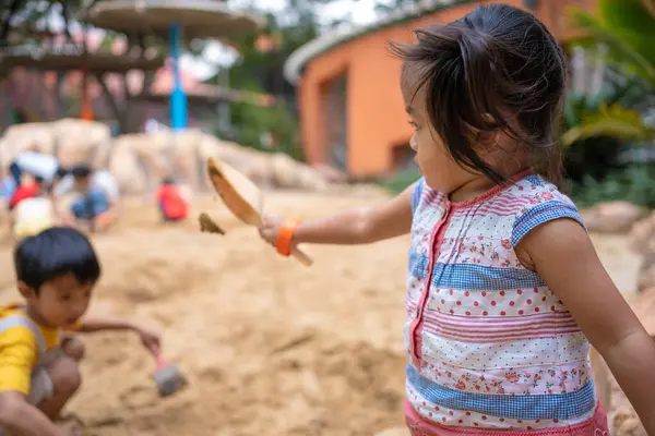 stock image Asian kindergarten boy and girl enjoy playing in sandbox having fun on playground in sandpit. Outdoor creative activities