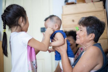 Mutlu gülümseyen büyükanneler küçük torunlarını rahat bir odada taşıyarak aile zamanlarının tadını çıkarırlar.