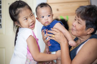 Mutlu gülümseyen büyükanneler küçük torunlarını rahat bir odada taşıyarak aile zamanlarının tadını çıkarırlar.