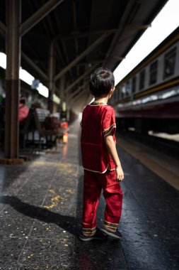 Küçük Asyalı çocuk geleneksel takım elbise giyer. Eski tren istasyonu Bangkok Tayland 'a gider.