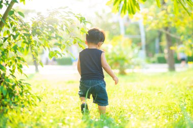 Yeni yürümeye başlayan Asyalı 1-2 yaşındaki çocuk ilk kez dışarıda yürüyor çayır çimenlerde gün batımında mutlu yeni bir hayat kavramı