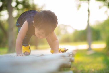 Yeni yürümeye başlayan Asyalı 1-2 yaşındaki çocuk ilk kez dışarıda yürüyor çayır çimenlerde gün batımında mutlu yeni bir hayat kavramı