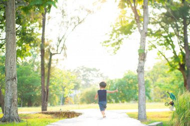 Yeni yürümeye başlayan Asyalı 1-2 yaşındaki çocuk ilk kez dışarıda yürüyor çayır çimenlerde gün batımında mutlu yeni bir hayat kavramı