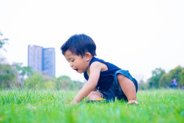 Yeni yürümeye başlayan Asyalı 1-2 yaşındaki çocuk ilk kez dışarıda yürüyor çayır çimenlerde gün batımında mutlu yeni bir hayat kavramı
