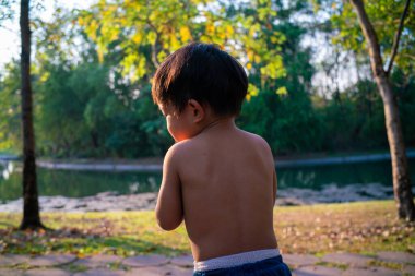 Küçük Asyalı çocuk şehir parkında gün batımında eğleniyor.