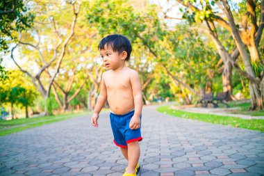 Küçük Asyalı çocuk şehir parkında gün batımında eğleniyor.