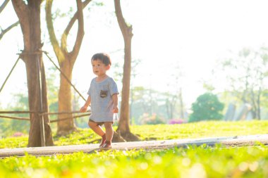 Yeni yürümeye başlayan Asyalı 2 yaşındaki çocuk yeşil çimlerde yürümenin keyfini çıkarıyor.