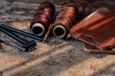 Hakiki inek derisinden cüzdan tutucu ahşap işçiliği objesinde deri aletlerle çalışıyor.