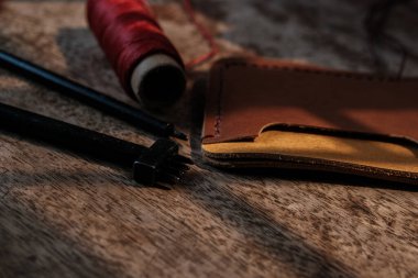 Hakiki inek derisinden cüzdan tutucu ahşap işçiliği objesinde deri aletlerle çalışıyor.