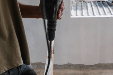 Yeni bina binasının ahşap kapısında elektrikli matkapla çalışan marangoz.