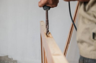 Yeni bina binasının ahşap kapısında elektrikli matkapla çalışan marangoz.