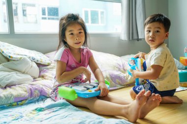 Küçük anaokulu çocuklarının halının üzerinde oyuncak oynamalarından mutlu. Mutlu, duygusal bir şekilde oturma odasında oyun oynuyorlar..